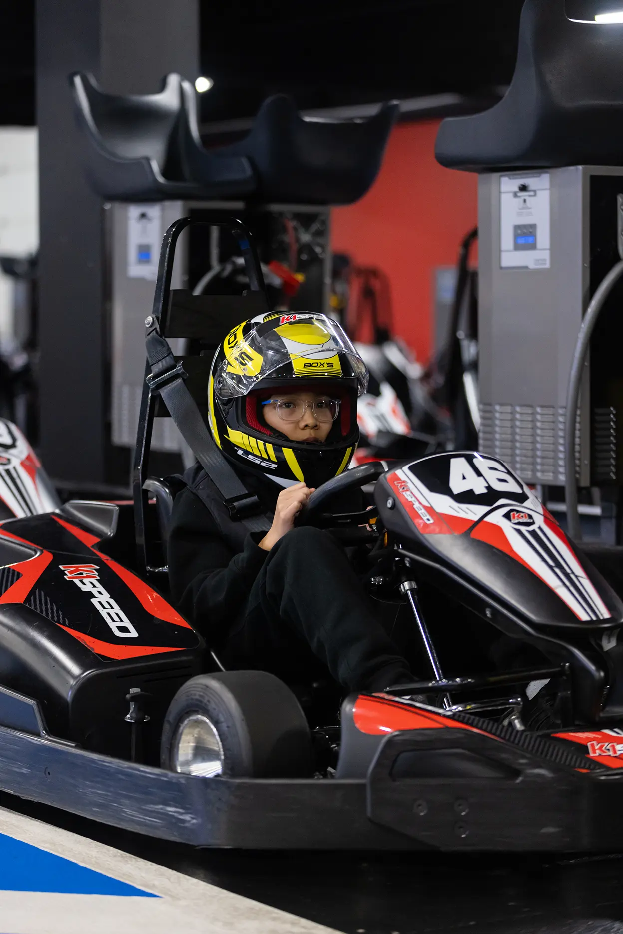 Young child wearing a helmet seated in an indoor go-kart
